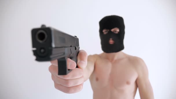 Террорист с обнаженным туловищем в балаклаве целится из пистолета на белом фоне — стоковое видео