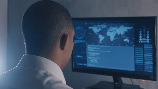 Back view of man programmer in white shirt working at computer in the data center — Stock Video