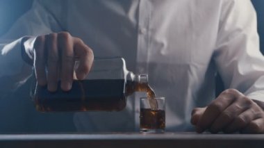 Barda tek başına bardaktan viski içen yakın çekim adam. Alkolizm kavramı.