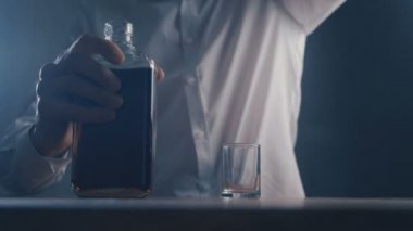 Barda tek başına bardaktan viski içen yakın çekim adam. Alkolizm kavramı.
