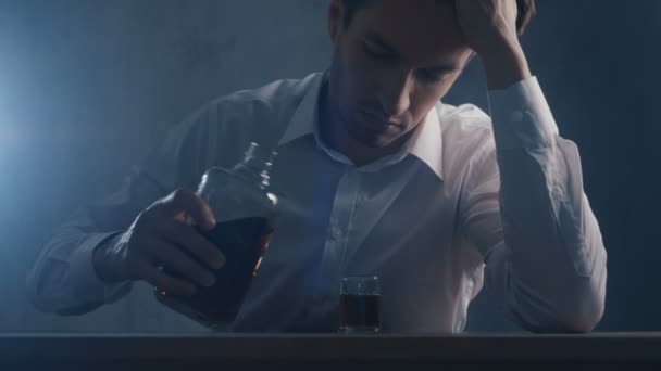 Un homme d'affaires déprimé verse du whisky dans un verre à boire seul dans une pièce sombre. Concept d'alcoolisme . — Video
