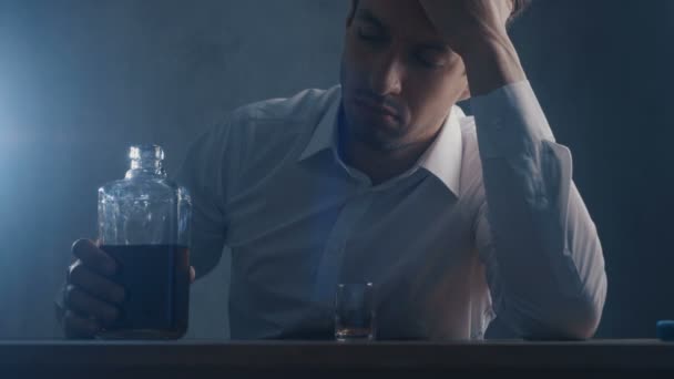 Ένας θλιμμένος επιχειρηματίας χύνεις ουίσκι σε ένα γυάλινο γυαλί πίνοντας μόνος σε ένα σκοτεινό δωμάτιο. Έννοια του αλκοολισμού. — Αρχείο Βίντεο