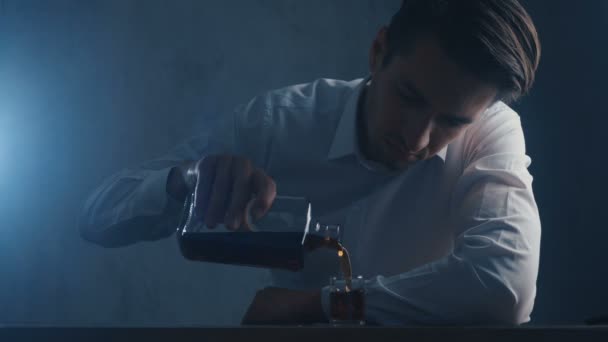 Un homme d'affaires déprimé verse du whisky dans un verre à boire seul dans une pièce sombre. Concept d'alcoolisme . — Video