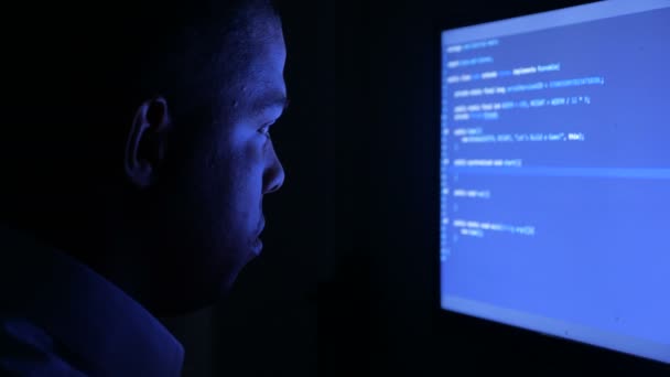 Porträt eines afrikanisch-amerikanischen Programmierers, der Netzwerksicherheitssoftware programmiert. Hacker tippen nachts Code auf Computerbildschirm im dunklen Büro — Stockvideo