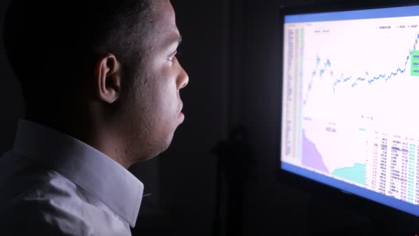 Close up of a young and busy african businessman working on computer at night. — Stock Video