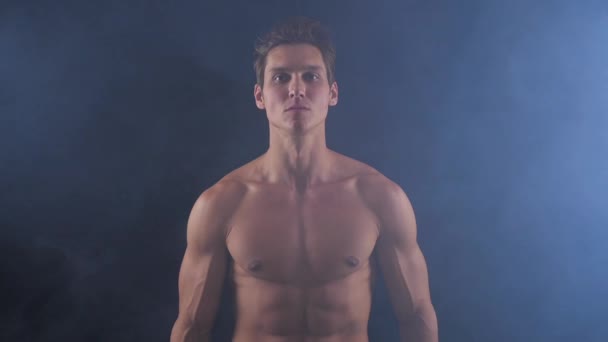 주위 연기와 어두운 배경에 서 있는 잘생긴 shirtless 남자. — 비디오