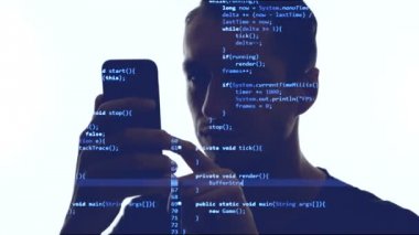 Üzerinde mavi kod olan akıllı telefonu kullanan bilgisayar korsanının çifte pozlaması. Akıllı telefon kullanarak adam programcı çift sergi