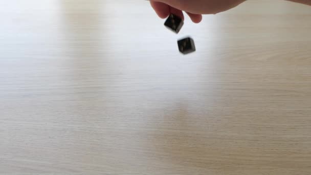 Rolling a pair of black gambling dice on a table in slow motion — Stock Video