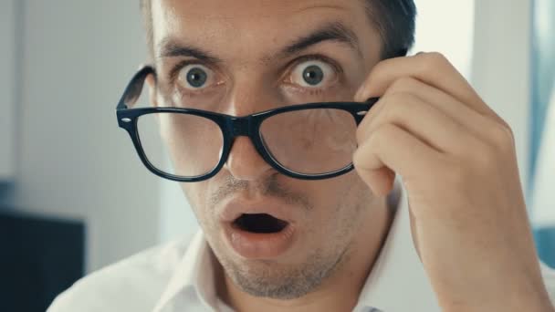 Mladý muž je šokován a překvapen. Muž v překvapení vystřelí brýle a překvapeně se podívá do kamery.. — Stock video