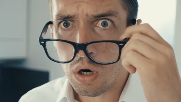 Young man is shocked and surprised. A man in surprise shoots glasses and looks at the camera in surprise. — Stock Video