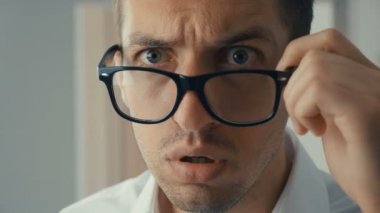 İşadamı şok oldu ve şaşırdı. Şaşkınlık içindeki bir adam gözlüğe ateş eder ve kameraya şaşkınlıkla bakar..