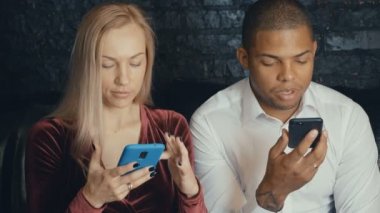 Kafe veya ofis arka planda akıllı telefon kullanan karışık ırk çift