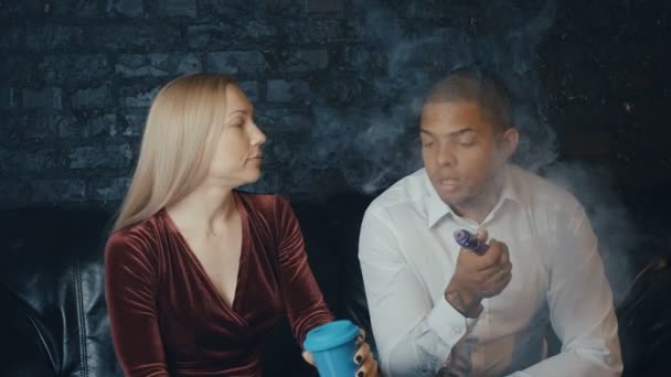 Багаторасова пара розмовляє в кав'ярні, чоловік курить вейп і жінка п'є каву в реанімації, різноманітні люди ведуть переговори на зустрічі в кафе — стокове відео