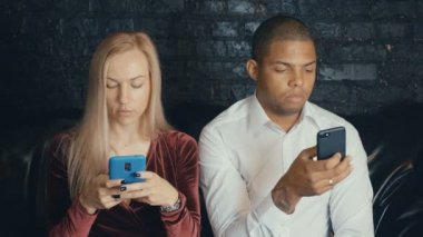 Kafe veya kafede smarkphone kullanarak çok ırklı çok ırklı meşgul çift.