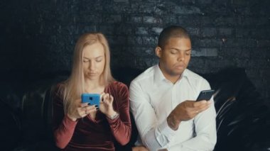 Kafe veya kafede smarkphone kullanarak çok ırklı çok ırklı meşgul çift.