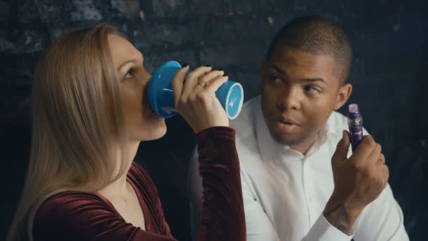 Young Couple talking in bar. Dating. Caucasian woman drinking coffee and black man smoking vape at bar — 비디오