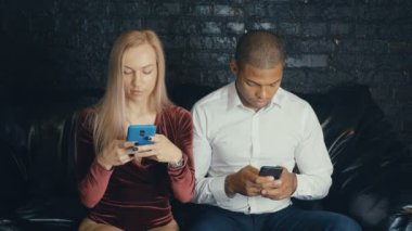 Kafe veya kafede smarkphone kullanarak çok ırklı çok ırklı meşgul çift.