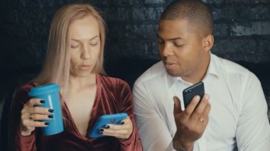 Kafe veya kafede smarkphone kullanarak çok ırklı çok ırklı meşgul çift.