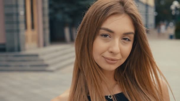 Linda mujer joven en la calle mira a la cámara, steadicam tiro. Hermoso retrato moda verano cara femenina de cerca — Vídeo de stock