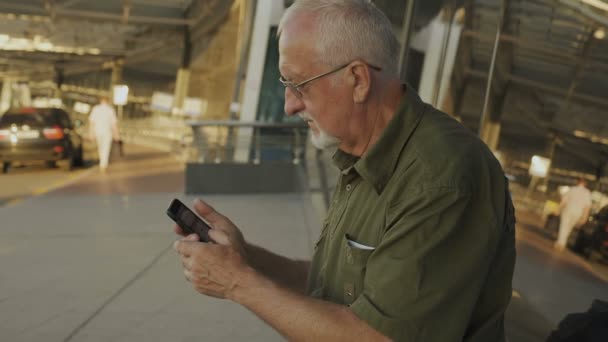 Uomo anziano utilizzando smartphone all'aperto — Video Stock