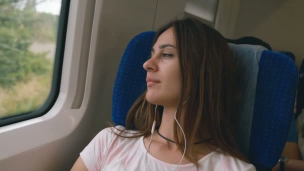 Pensive jonge vrouw die uit een trein venster kijkt. Reizen, transport concept — Stockvideo