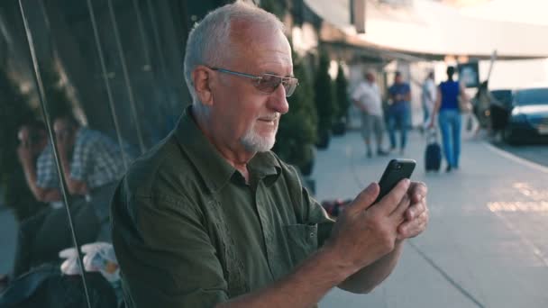 Empresário sênior usando smartphone ao ar livre no terminal do aeroporto — Vídeo de Stock