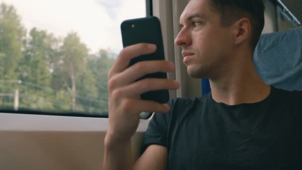 Jeune homme utilisant son smartphone, enregistrement et défilement pendant le trajet en train — Video