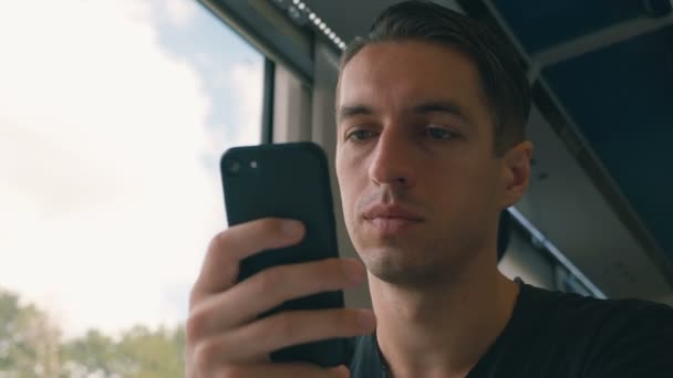 Νέος άνθρωπος που χρησιμοποιεί το smartphone του, μαγνητοσκόπηση και κύλιση κατά τη διάρκεια της διαδρομής του τρένου — Αρχείο Βίντεο