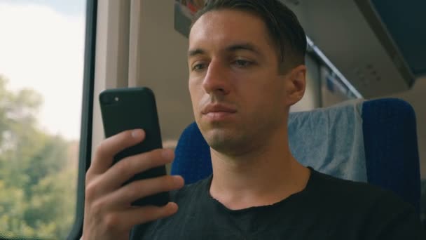 Genç adam onun akıllı telefon kullanarak, kayıt ve tren yolculuğu sırasında kaydırma — Stok video