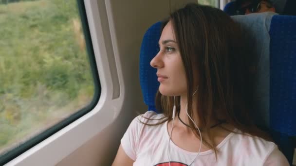 Pensive jonge vrouw die uit een trein venster kijkt. Reizen, transport concept — Stockvideo