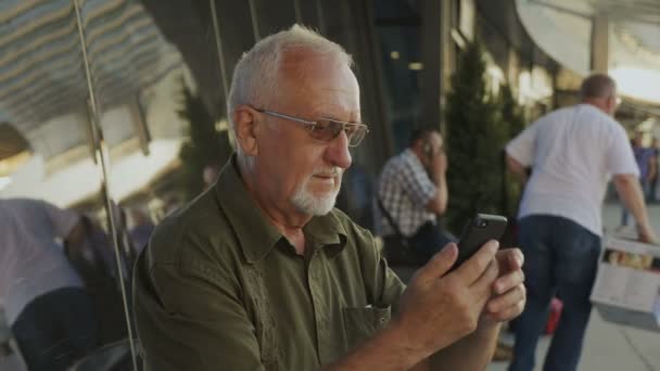 Senior man met smartphone buitenshuis — Stockvideo