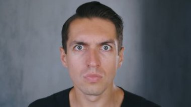 Genç adam, güvensizlik ve sürpriz kayıt kameraya bakarak ve sonra korkmuş bakıyor.