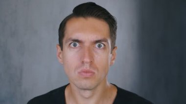 Genç adam, güvensizlik ve sürpriz kayıt kameraya bakarak ve sonra korkmuş bakıyor.