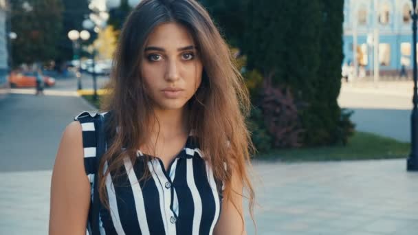 Ritratto di bella giovane donna modello bruna guardando la macchina fotografica su uno sfondo urbano. Ragazza con grandi occhi . — Video Stock