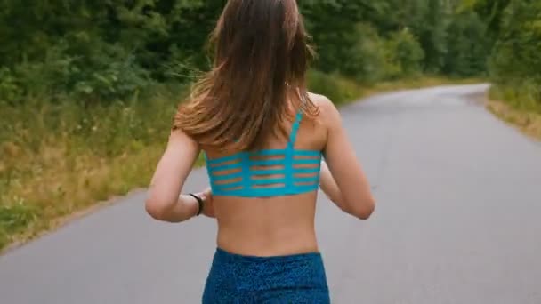 Vista posterior de la mujer joven corredor de formación en el parque de verano. Chica de fitness corriendo al aire libre. Concepto de mañana . — Vídeos de Stock