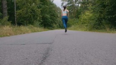 Koşucu kadın yavaş hareket halinde ormanda yolda koşuyor. açık fitness. Steadicam ile vuruldu. Sabah çalışan kavramı.