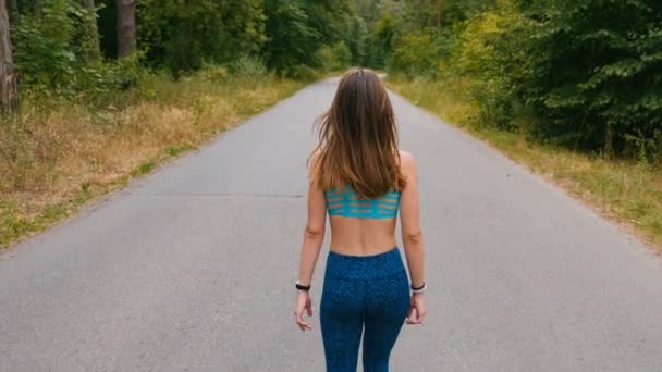 Sexy Mädchen zu Fuß auf der Straße im Wald. Fitness im Freien. Schuss mit Schwebestativ — Stockvideo