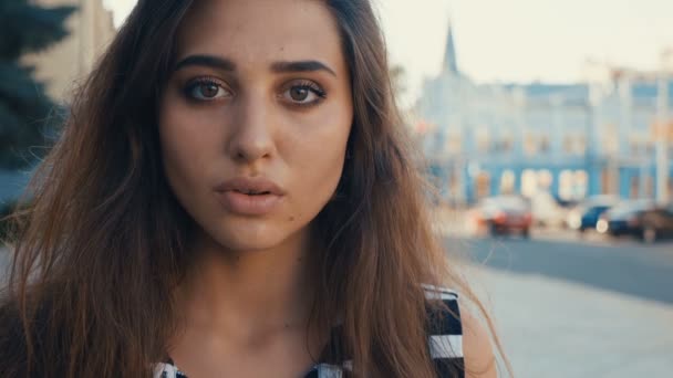 Närbild porträtt av vacker ung kvinna brunett modell tittar på kameran på en stad gatubakgrund. Flicka med stora ögon. — Stockvideo
