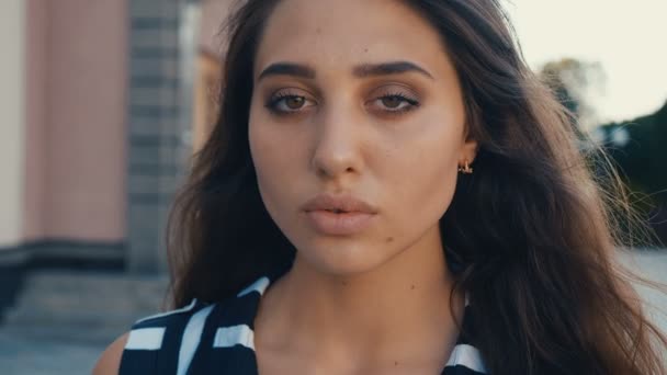 Close-up portret van mooie jonge vrouw brunette model kijkend naar de camera op een stads straat achtergrond. Meisje met grote ogen. — Stockvideo