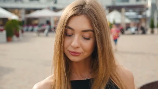 Face light brown haired young woman looking at camera close up. Portrait beautiful woman on urban city street background. — Stock Video