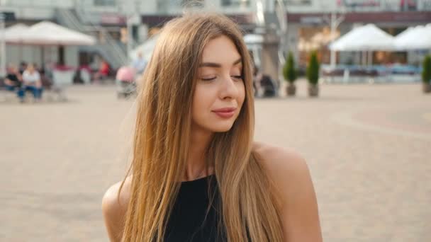 Portrait de jeune femme aux cheveux brun clair regardant la caméra de près. Belle femme sur fond de rue urbaine . — Video