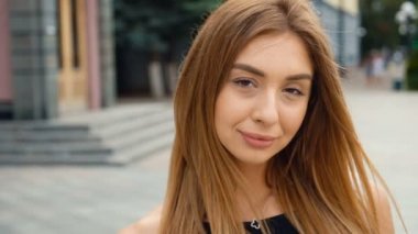 Yüz açık kahverengi saçlı Genç kadın kamera Steadicam vurdu bakıyor. Kentsel şehir sokak arka planda portre güzel kadın.