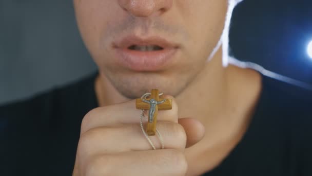 Close-up van jonge man bidden tot God die een kruis in zijn hand houdt. Begrip geloof en religie — Stockvideo