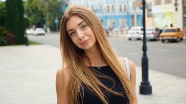 Yüz açık kahverengi saçlı Genç kadın kamera Steadicam vurdu bakıyor. Kentsel şehir sokak arka planda portre güzel kadın.