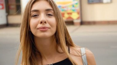 Yüz açık kahverengi saçlı Genç kadın kamera Steadicam vurdu bakıyor. Kentsel şehir sokak arka planda portre güzel kadın.