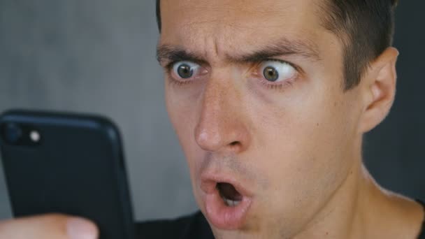 Člověk byl šokován špatnou zprávou, kterou četl na svém telefonu. Zblízka šokovaný a ohromený muž. — Stock video