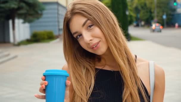 Portret van mooie jonge vrouw in de stad. Glimlachend gelukkig. Heerlijke koffie drinken. — Stockvideo