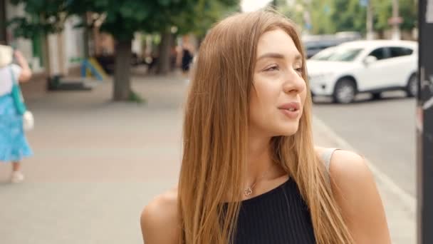 Gesicht hellbraunhaarige junge Frau, die auf Kamera-Steadicam-Aufnahme schaut. Porträt schöne Frau auf städtischen Straßen Hintergrund. — Stockvideo