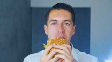 Bir hamburger yiyen adamın zaman doluğu. Hızlı yemek. Cheeseburger, hamburger, sandviç.
