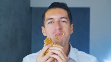 Bir hamburger yiyen adamın zaman doluğu. Hızlı yemek. Cheeseburger, hamburger, sandviç.